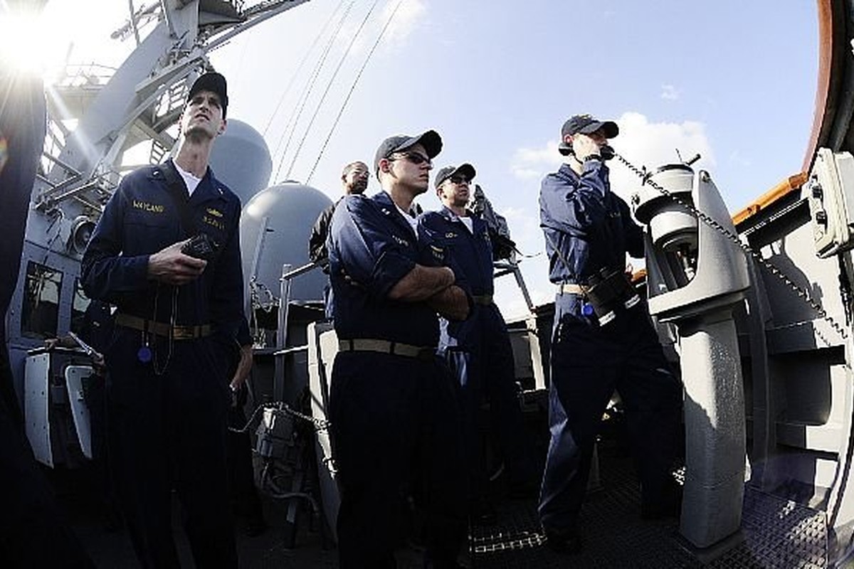 Sailors on the bridge wing of a Navy destroyer during an underway replenishment.