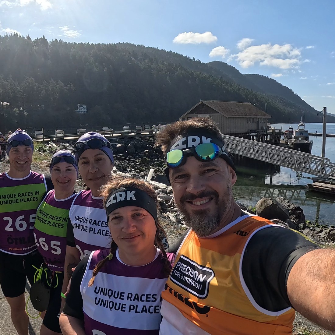 Wes with teammates at an Ötillö Swimrun start, harbor and mountains in the background.